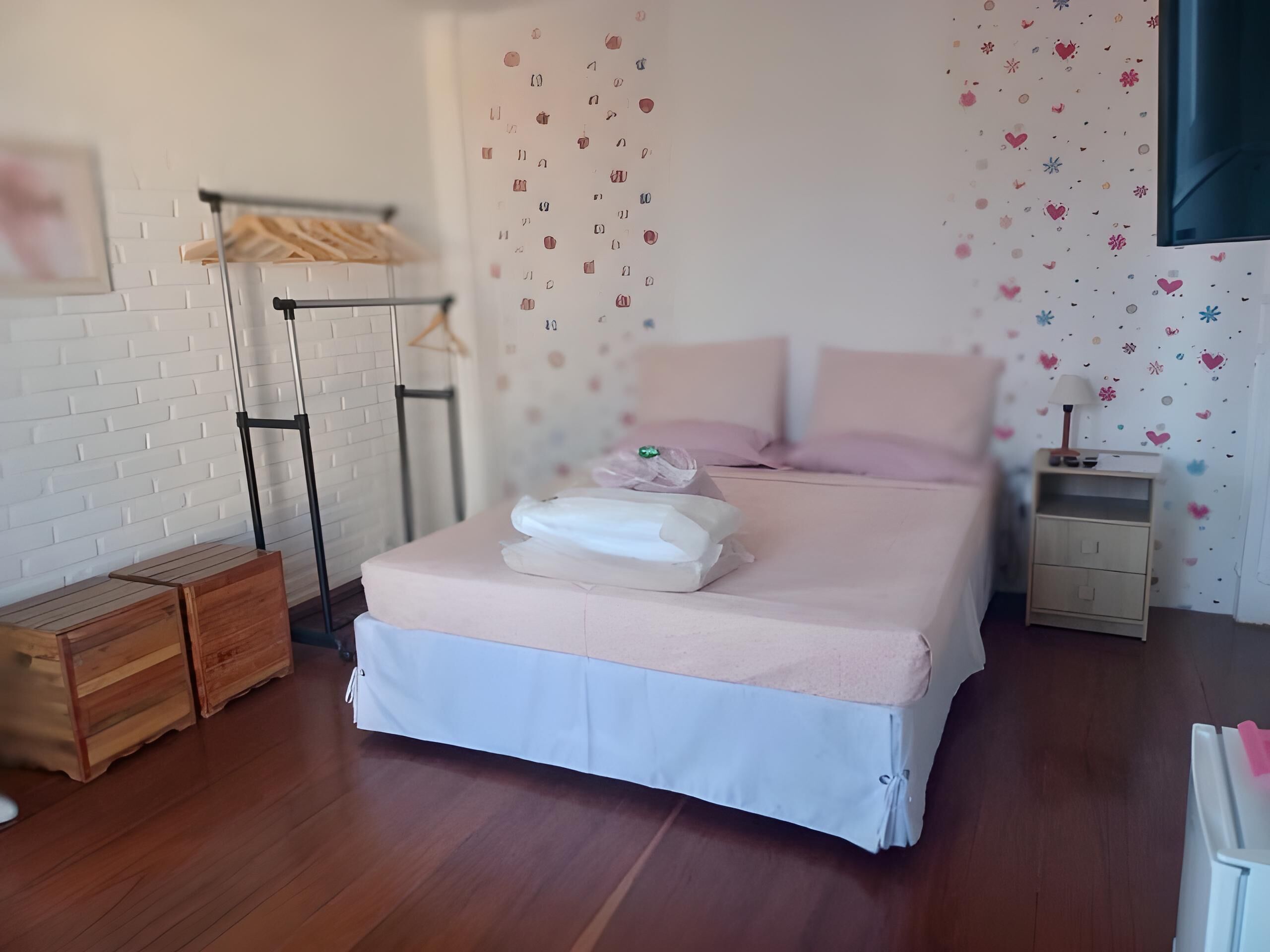A neatly arranged bedroom with a bed, bedside tables, and a wardrobe.