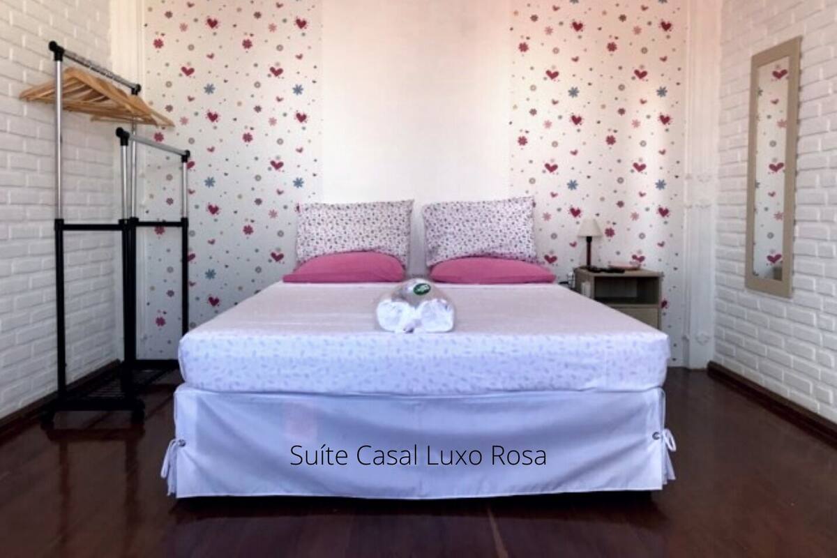 Un dormitorio con cama, mesita de noche, espejo y perchero.