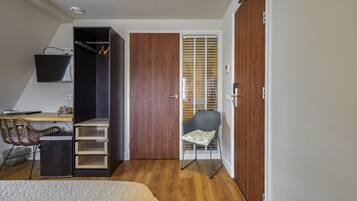 Ein Schlafzimmer mit einem Bett, einem Schreibtisch, einem Stuhl, einem Kleiderschrank und einer Schiebetür zum Balkon.
