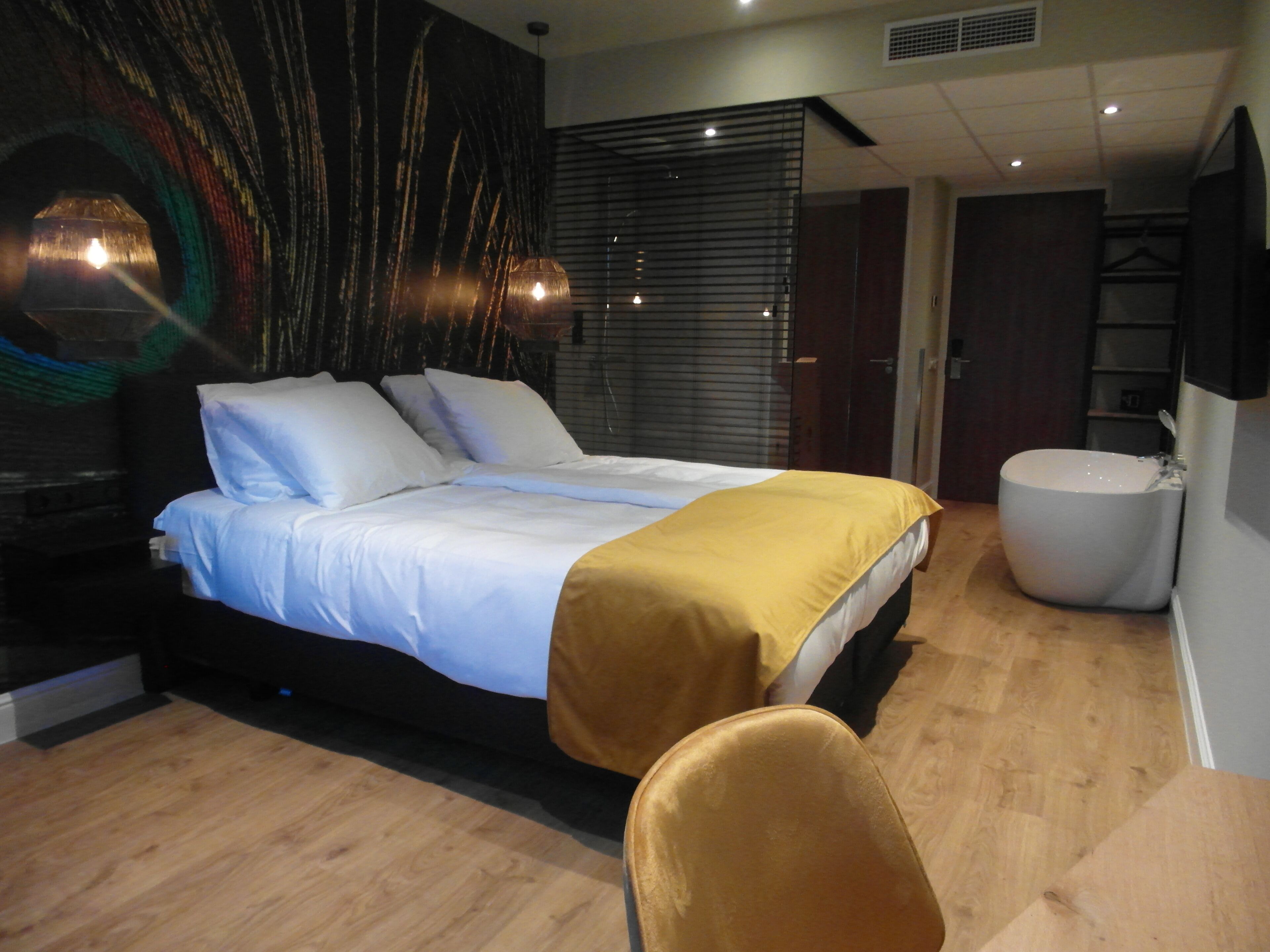 Un dormitorio moderno con una cama grande, una mesita de noche, una silla y un baño con bañera.
