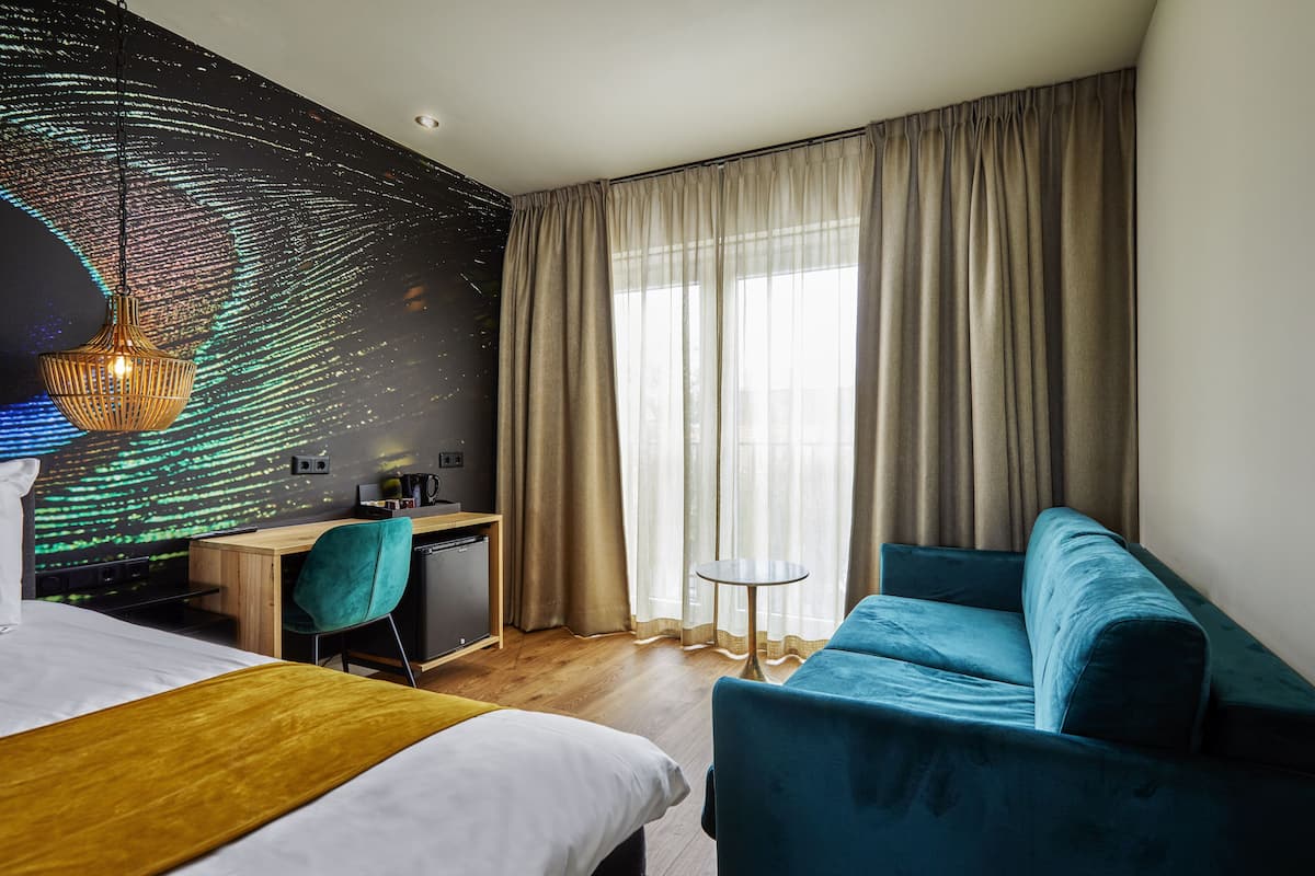 Een hotelkamer met een bed, een bureau, een stoel en een bank.