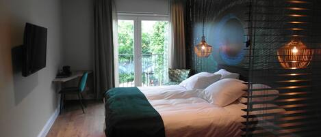 Quarto moderno com uma cama grande, uma escrivaninha e vista para o verde lá fora.