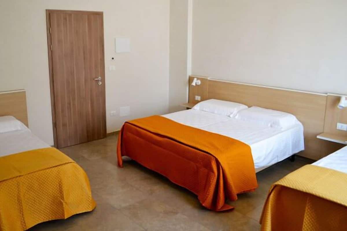 A hotel room with two single beds, each with a wooden headboard, and a brown door.