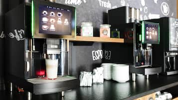 Een koffiebar toonbank met espresso machines, een digitaal menubord en een prikbord met verschillende koffie-gerelateerde tekeningen.