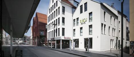 Un hotel moderno con un llamativo letrero que dice 'RKU Hotel', una entrada visible y una calle despejada.