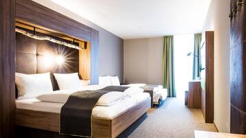 A modern hotel room with a large bed, a smaller bed, and a desk.