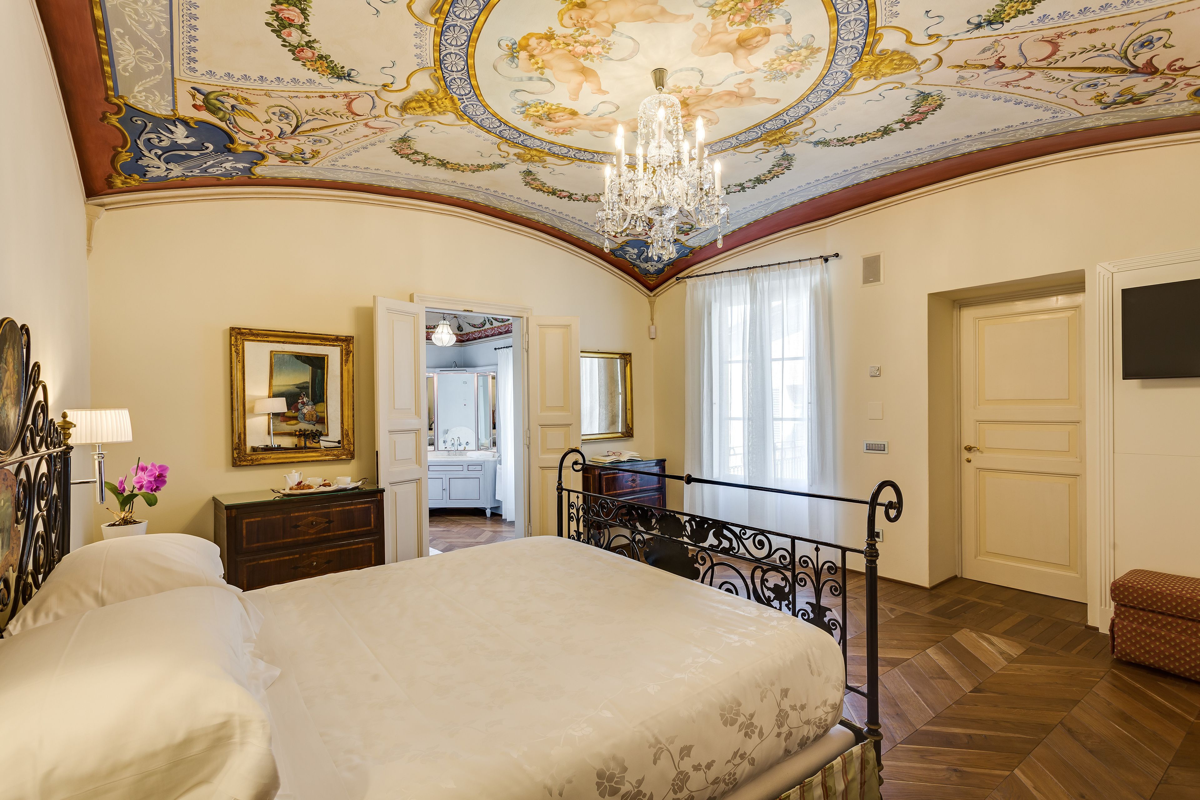 Un dormitorio con una cama grande, una araña y un techo con detalles artísticos.