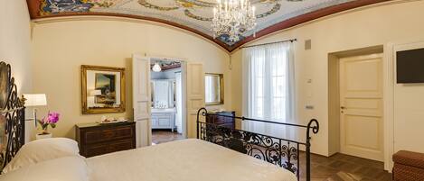Un dormitorio con una cama grande, una araña y un techo con detalles artísticos.