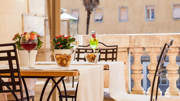 A table set for two with a wine glass, a bowl of nuts, and a glass of water. - Relais degli Angeli (Siena)