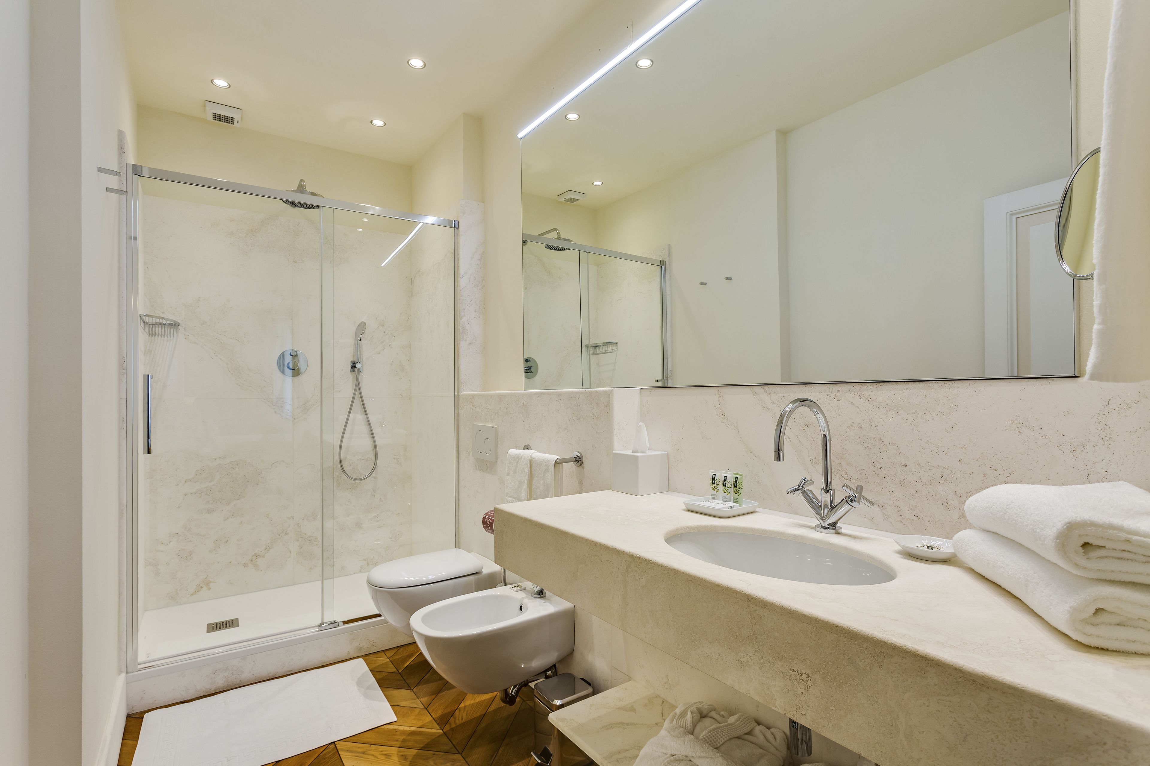 A modern bathroom with a glass-enclosed shower, a sink with a mirror, and a toilet.