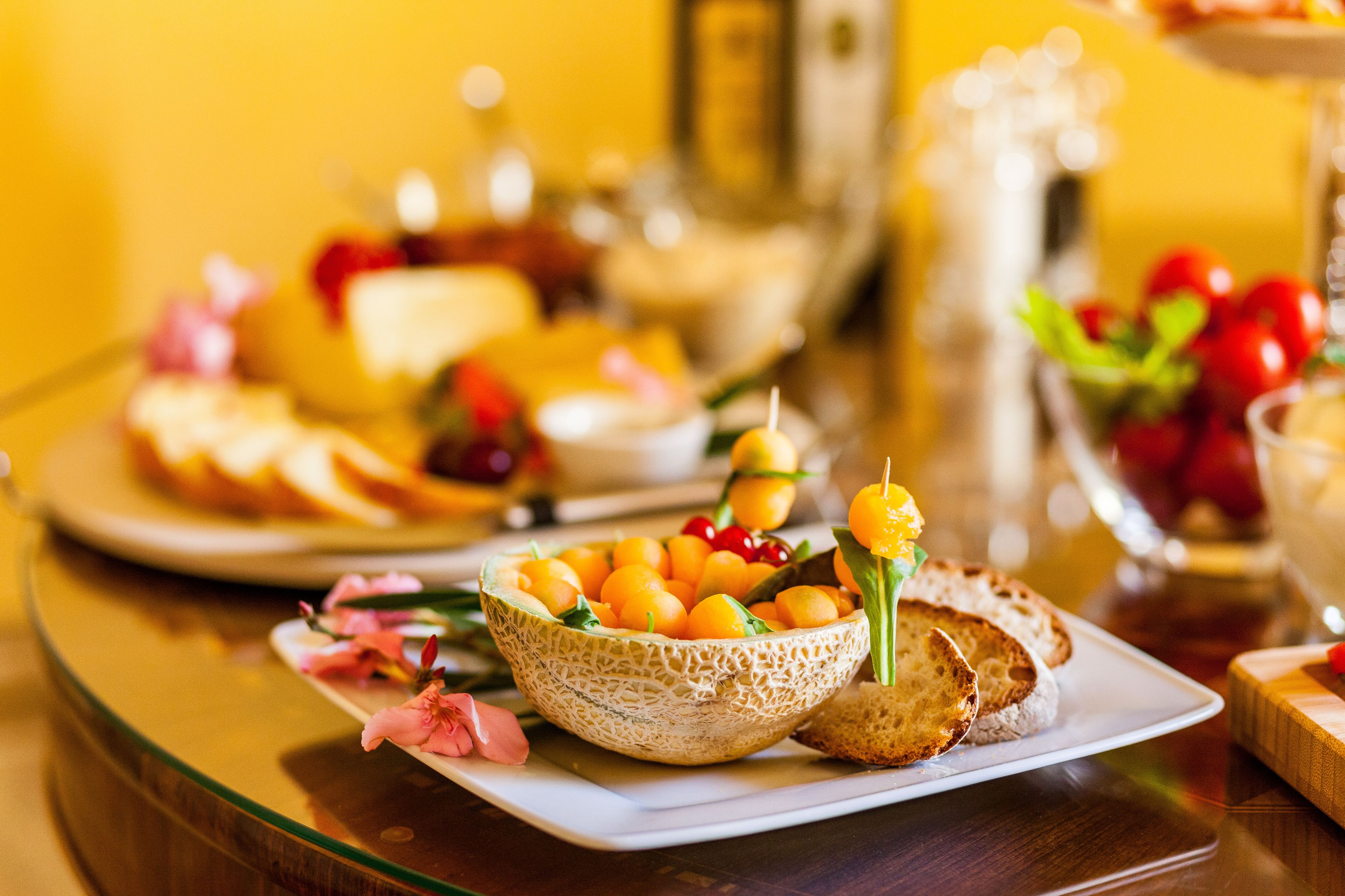 A table with a variety of food items including a bowl of fruit, bread, and a glass of juice.