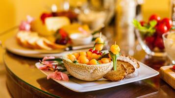 Une table sur laquelle on trouve une variété d’aliments, notamment un saladier de fruits, du pain et un verre de jus.