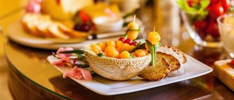 A table with a variety of food items including a bowl of fruit, bread, and a glass of juice.