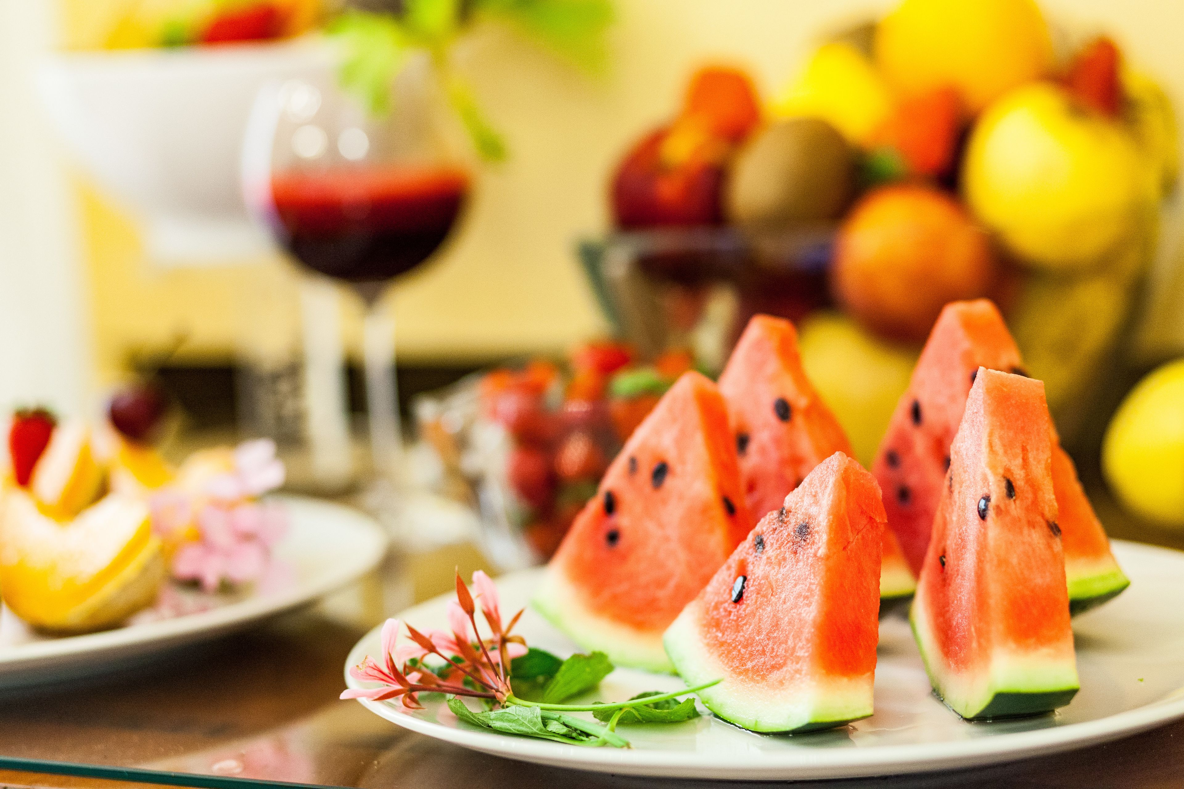 A table with watermelon slices, a glass of red drink, and various fruits.