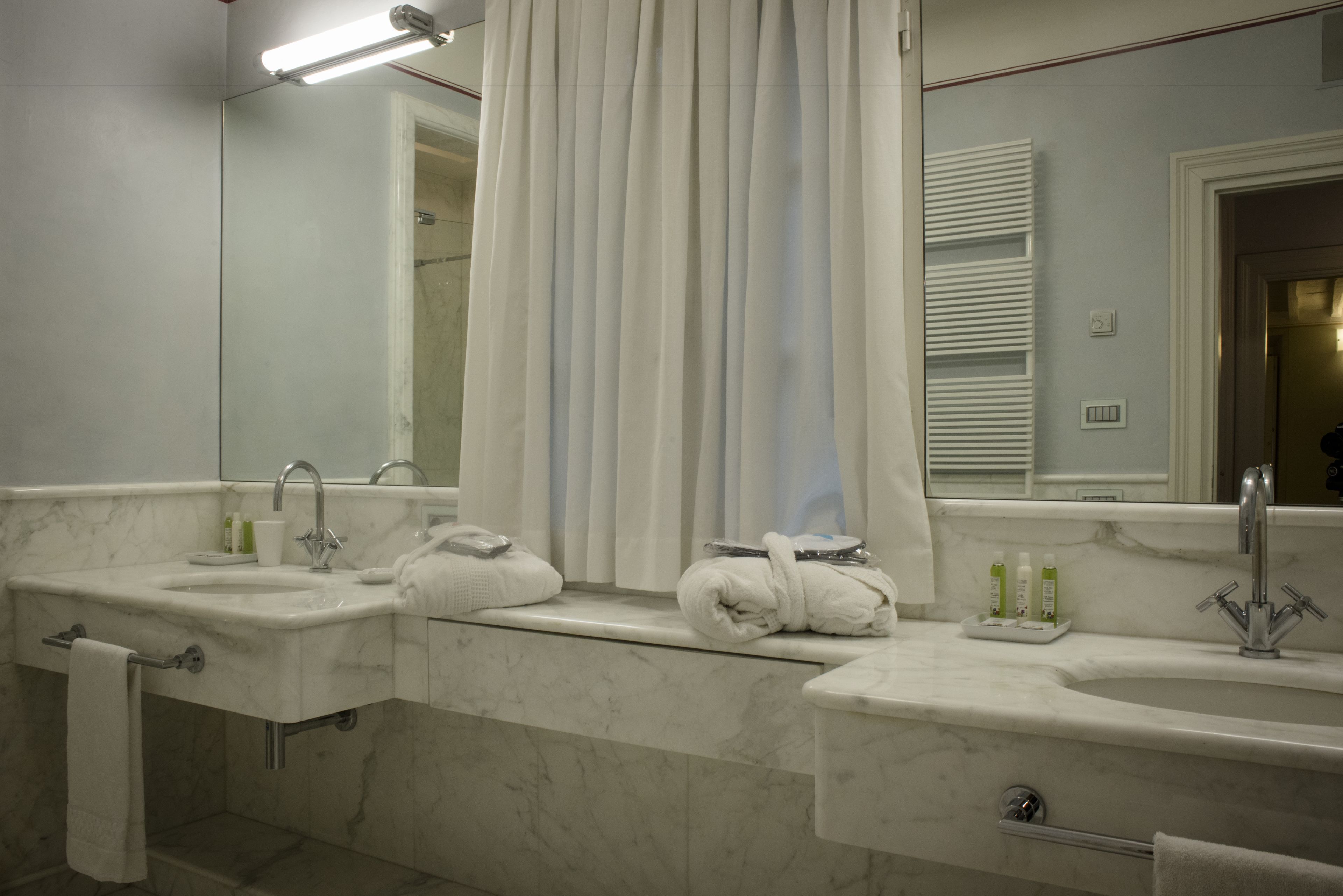 A bathroom with two sinks, a shower, and a large mirror.