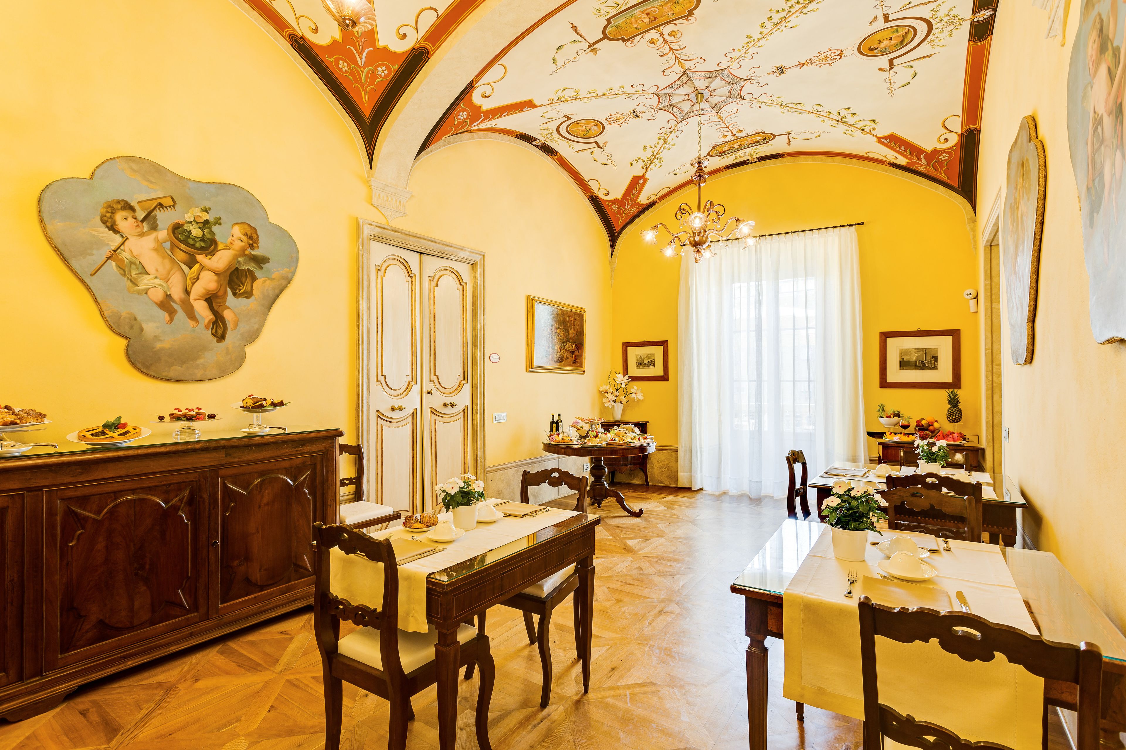A dining room with wooden furniture, a chandelier, and a ceiling with intricate designs.