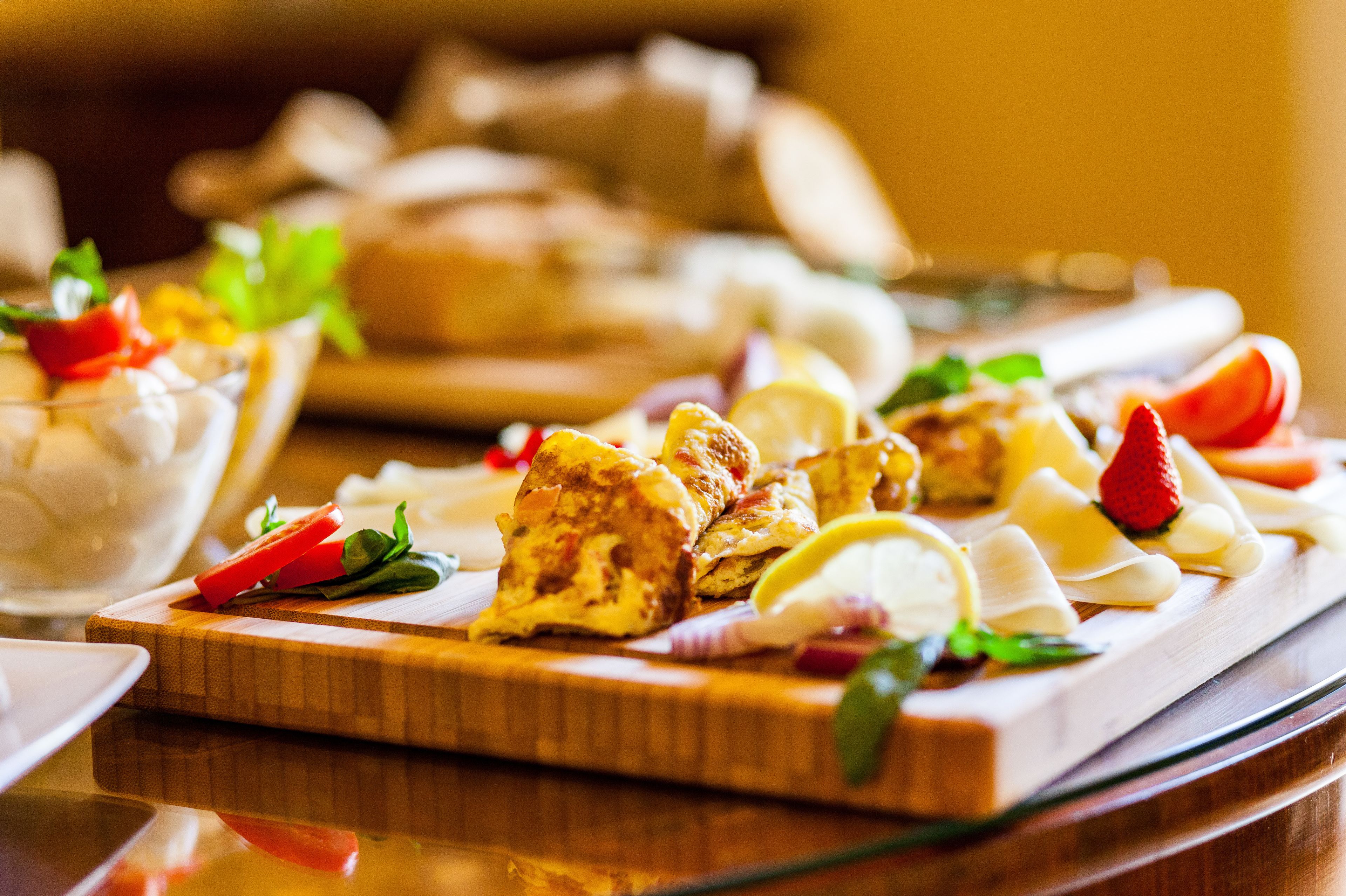 Una tabla de madera con diversos alimentos, como pan y verduras, sobre una mesa.