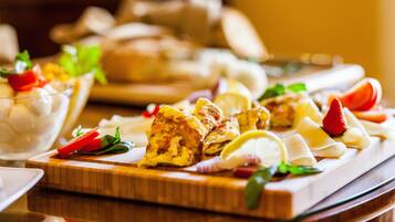 A wooden board with various food items, including bread and vegetables, on a table.