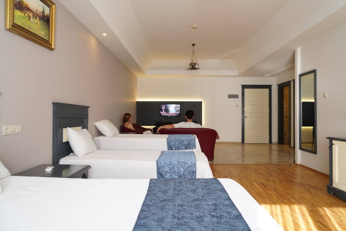 Una habitación de hotel con dos camas, televisor y piso de madera.