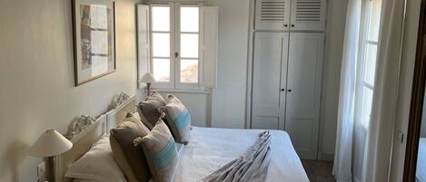 Un dormitorio con cama, ventilador de techo, ventana y puerta.