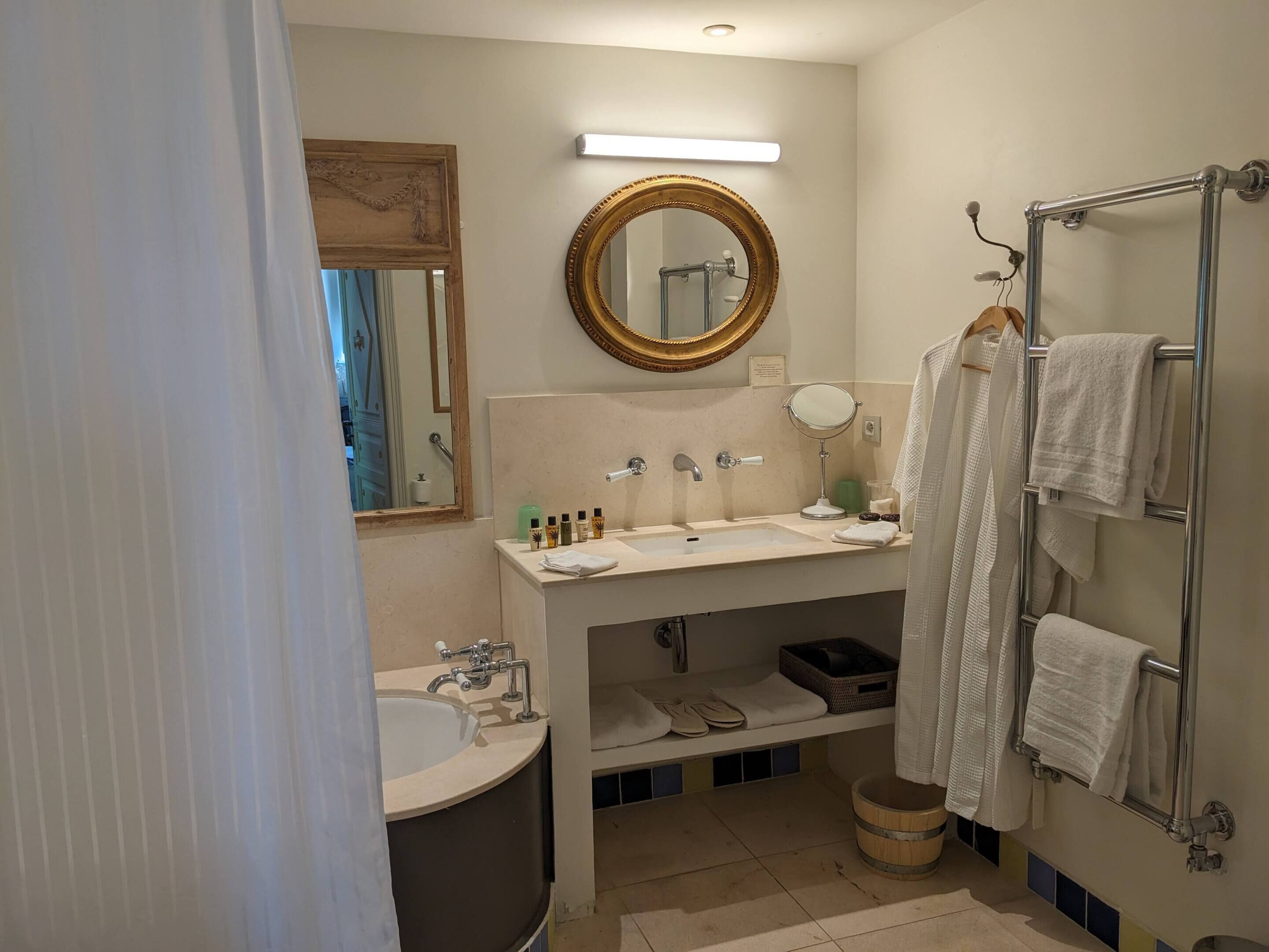 Un baño con lavamanos, espejo, toallero y zona de ducha.
