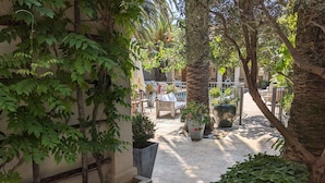 A courtyard with a seating area, potted plants, and a palm tree. - Pastis Hotel Saint-Tropez (Saint-Tropez)