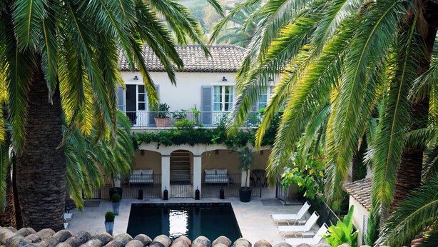 A courtyard with a pool, palm trees, and a building with a tiled roof and shutters. - Pastis Hotel Saint-Tropez (Saint-Tropez)