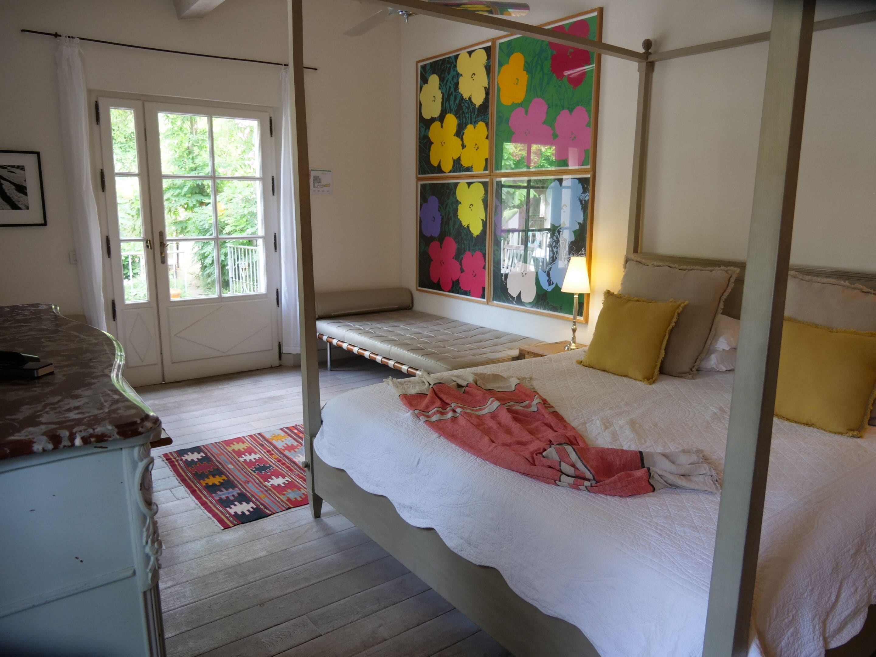 Een hemelbed met een witte spreidek en een kleurrijke bloemillustratie erboven.