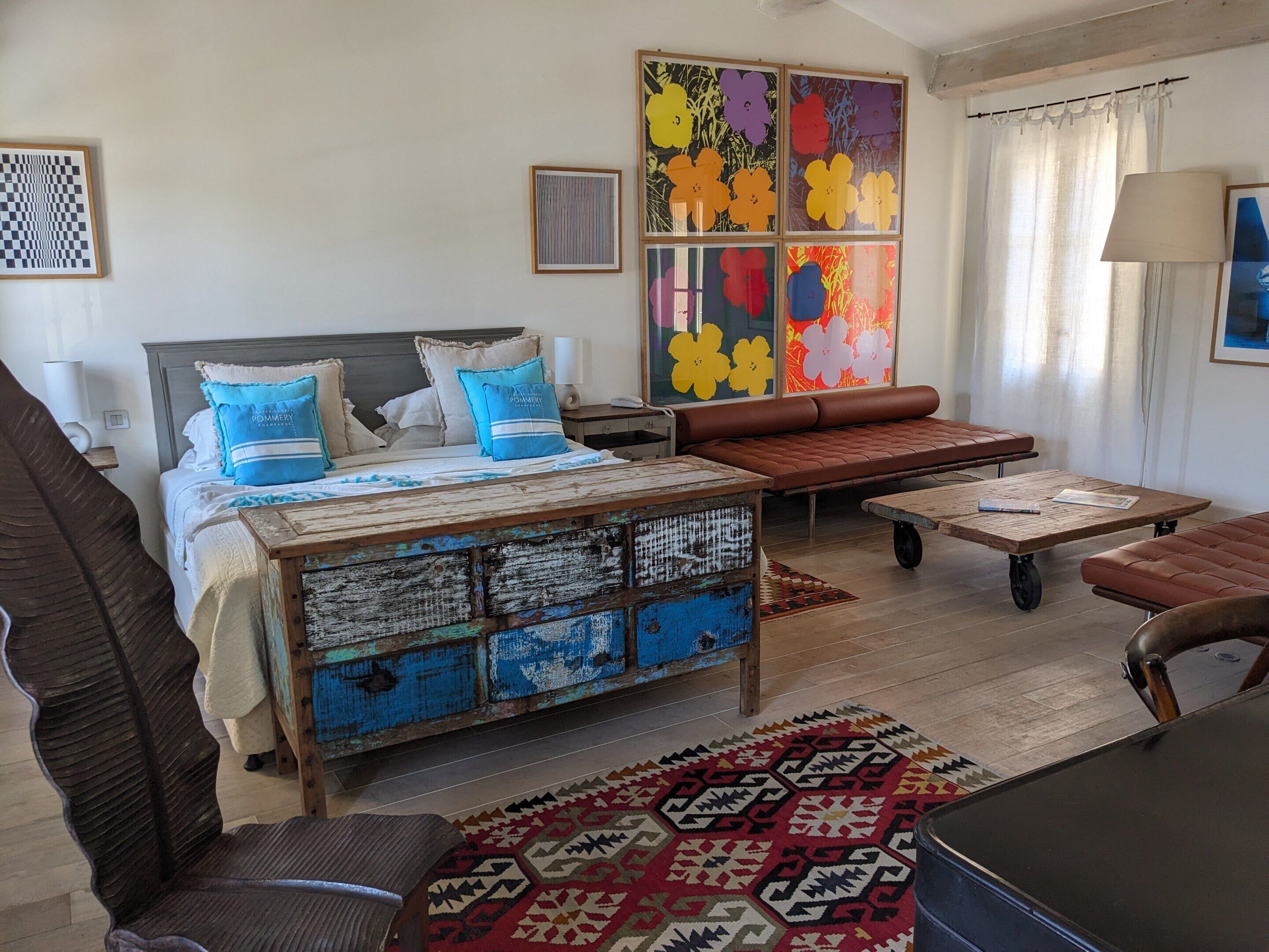 A bedroom with a bed, a wooden chest, a sofa, a coffee table, and a patterned rug.