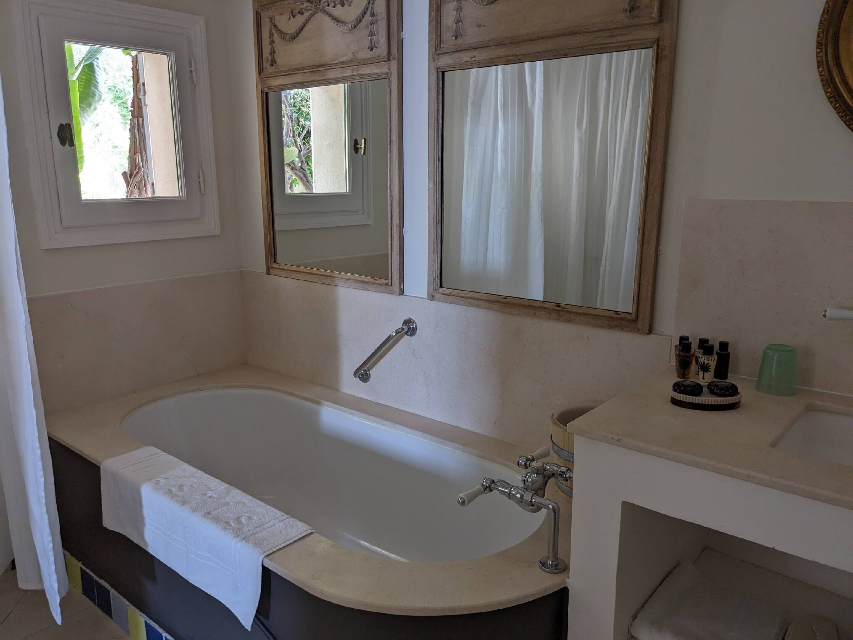 Ein Badezimmer mit einer Badewanne, einem Waschbecken und zwei Spiegeln.