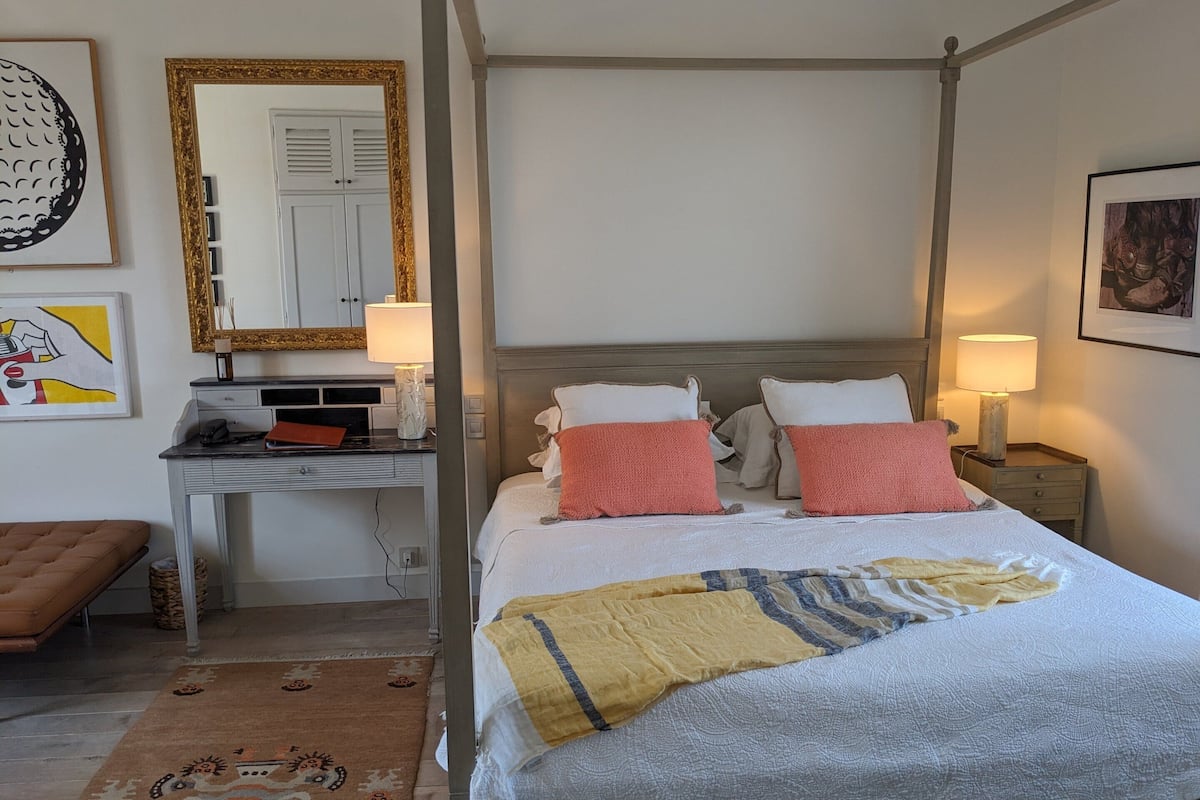 A neatly arranged bedroom with a bed, bedside tables, a desk, and a chair.