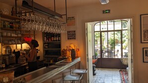 A bar area with stools, a counter, and shelves with bottles and glasses. - Pastis Hotel Saint-Tropez (Saint-Tropez)