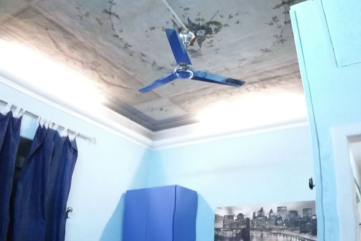 A room with a bed, a wardrobe, a ceiling fan, and a cityscape poster on the wall.