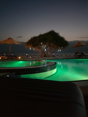 Una piscina al aire libre, sombrillas, sillones reclinables de piscina