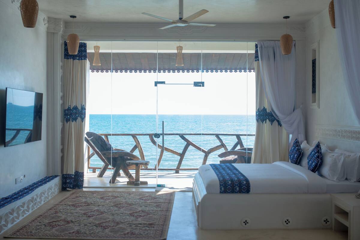Een slaapkamer met een groot bed, een televisie en uitzicht op zee.