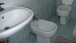 A bathroom with a sink, bidet, toilet, and a towel rack. - Walter Rooms (Rome)