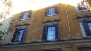 A yellow building with multiple windows and a visible balcony. - Walter Rooms (Rome)