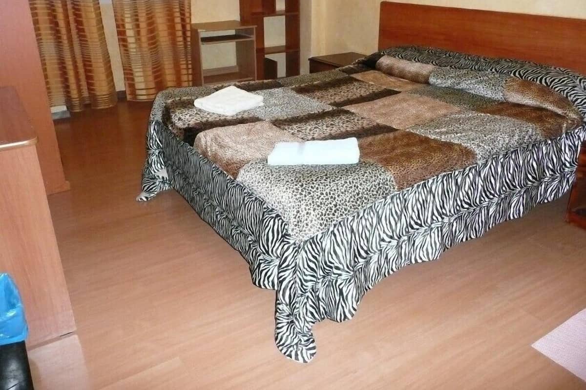 Una camera da letto con una coperta a motivi zebrati, una testiera in legno e un comodino.