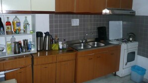 A compact kitchen with wooden cabinets, a gas stove, a sink, and various kitchen appliances. - Walter Rooms (Rome)