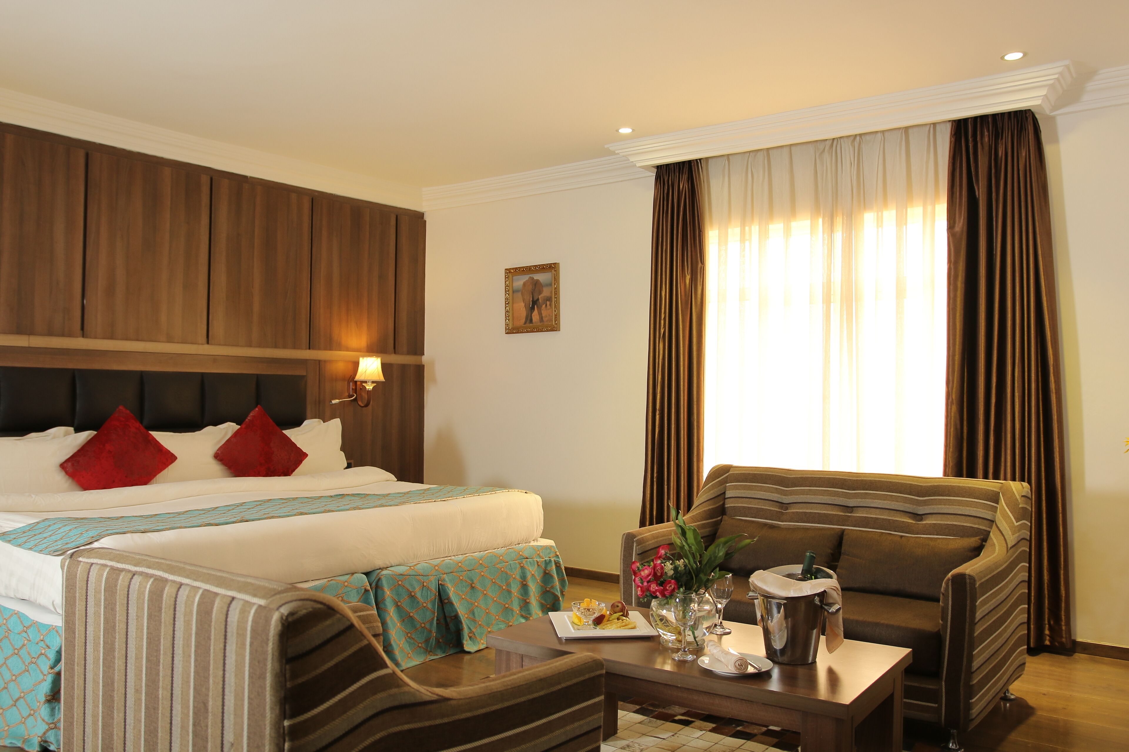 A hotel room with a bed, two armchairs, a coffee table, and a dining table.