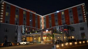 A hotel with a prominent 'Grand Pela' sign, multiple floors, and a well-lit entrance. - Grand Pela Hotels & Suites (Abuja)