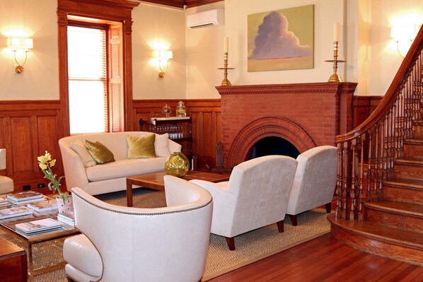 Una sala de estar con chimenea, una escalera y un sofá con cojines.