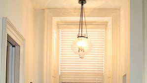 Une salle de bain avec un meuble-lavabo blanc, un grand miroir et un luminaire suspendu.
