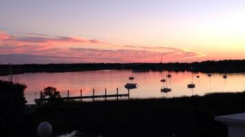 A calm lake at sunset with several boats anchored.