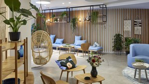 Una sala de estar moderna con suelo de madera, sofás azules, una silla colgante y diversas plantas.
