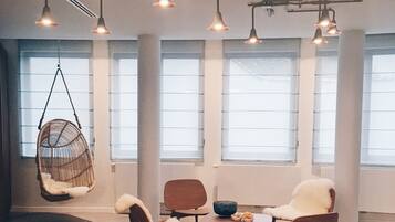 Un intérieur moderne avec des chaises suspendues, des tables en bois et de grandes fenêtres.