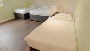 A room with two single beds, a small bedside table, and a wooden floor. - Primelodge Doncaster (Doncaster)