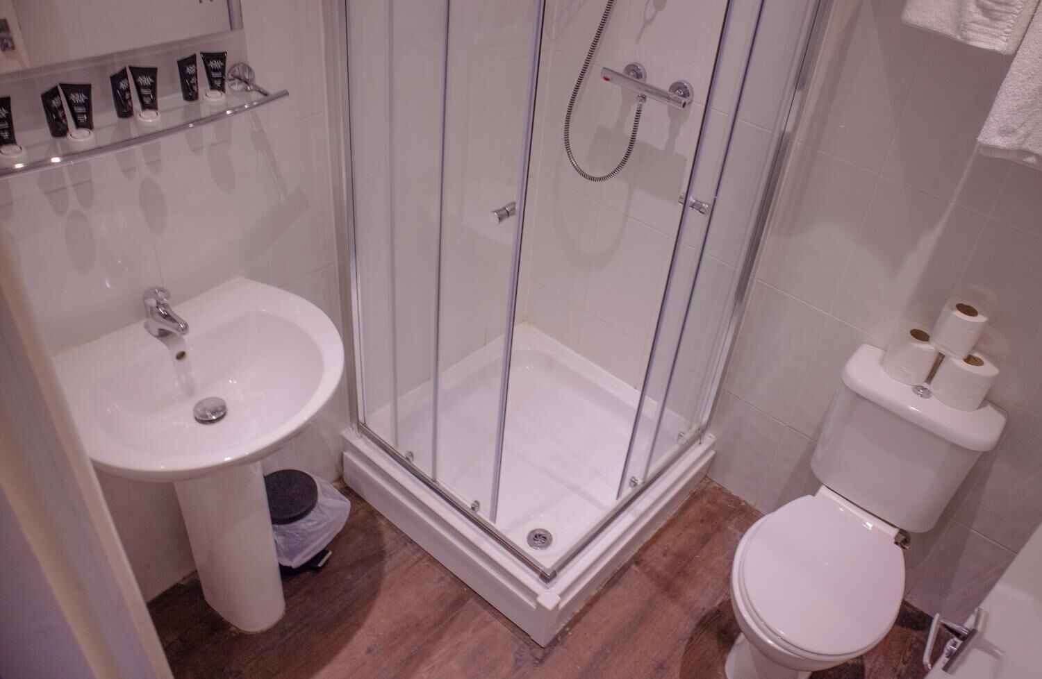 A bathroom with a glass-enclosed shower, a sink, and a toilet.