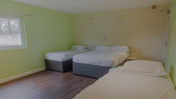 Habitación con dos camas, ventana y piso de madera.