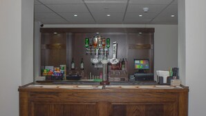 Zona de bar con varias botellas de licor, una caja registradora y un monitor de computadora.